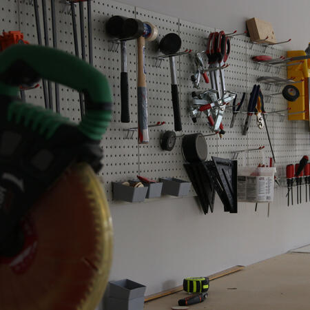 A photograph of hand-tools and power-tools in a workshop. The image has a shallow depth of field and is blurry in the foreground, but clear in the background.